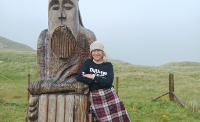 Woman wearing a kilt and standing next to A 3m high lewis chessmen sculpture