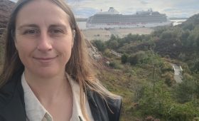 woman smiling with cruise ship in the background